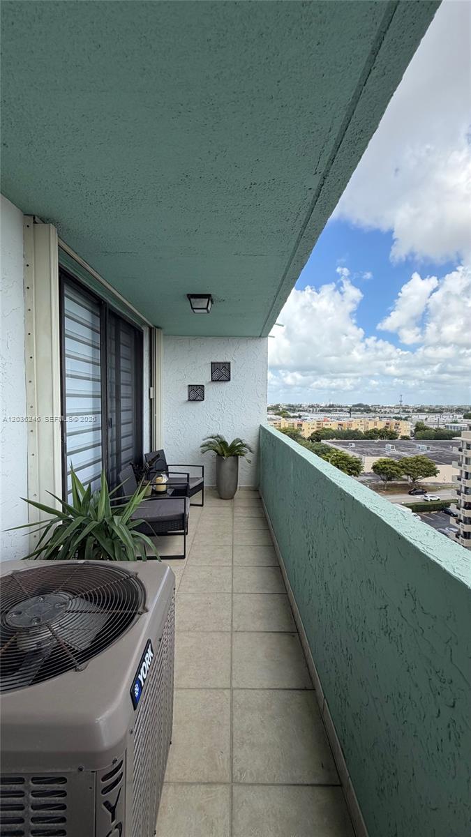 A balcony features a tiled floor, a York air conditioning unit, and a view of buildings — 1825 W 44th Pl # 1107, Hialeah FL 33012, HIALEAH, FL