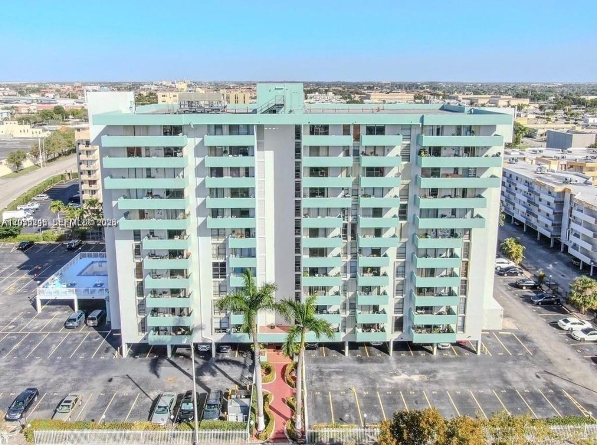 An aerial view of a multi-story apartment building with teal balconies and a parking lot — 1825 W 44th Pl # 1107, Hialeah FL 33012, HIALEAH, FL
