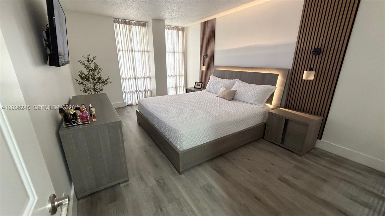 A bedroom features a platform bed, wood-slat wall panels, and light-colored wood flooring — 1825 W 44th Pl # 1107, Hialeah FL 33012, HIALEAH, FL
