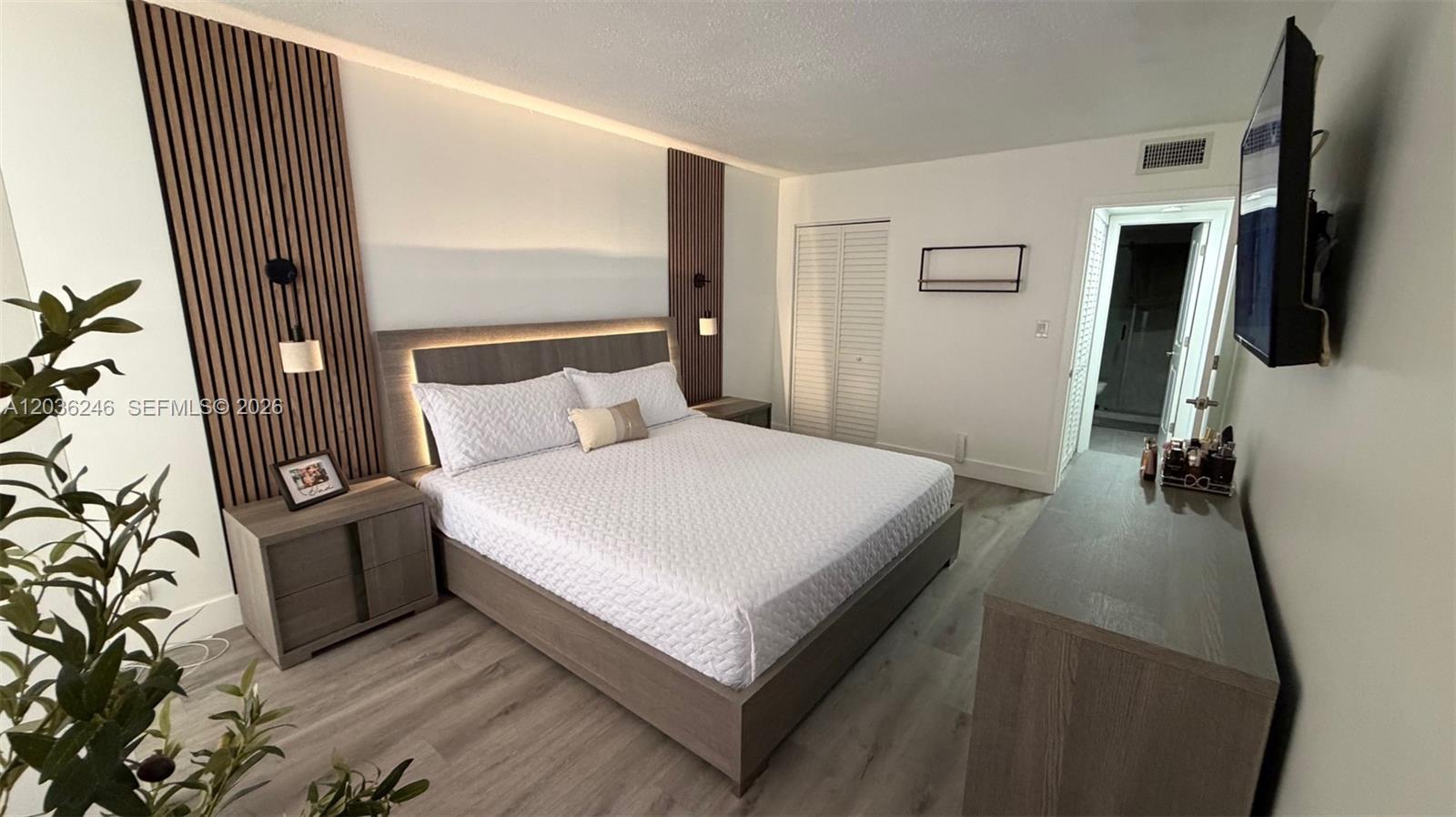A bedroom features a platform bed with wood-slat wall panels and light-colored wood flooring — 1825 W 44th Pl # 1107, Hialeah FL 33012, HIALEAH, FL