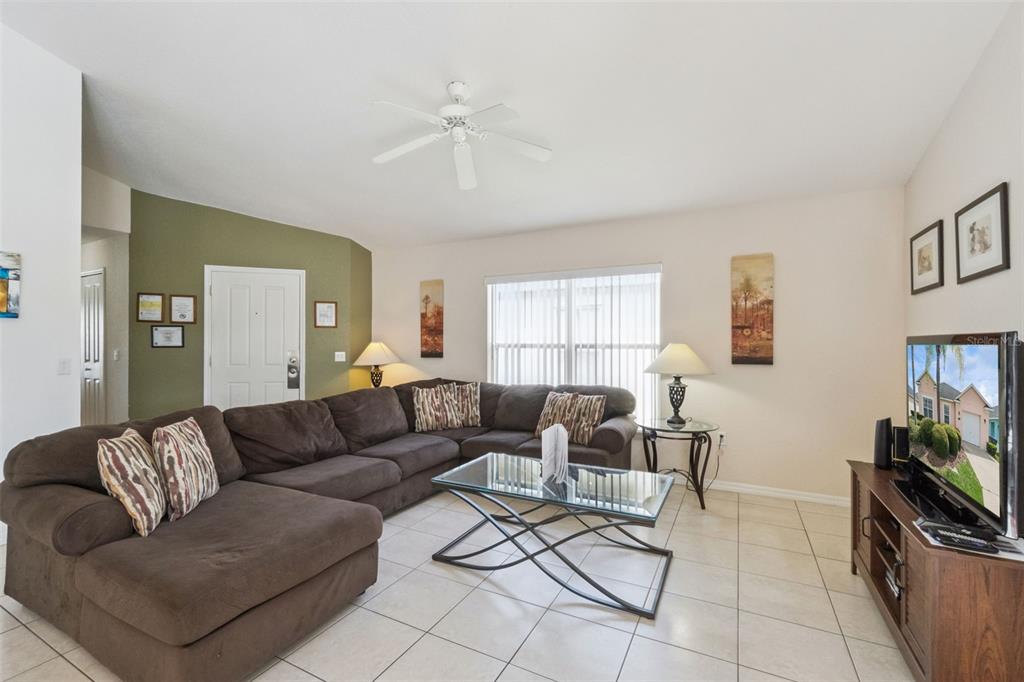 A living room features a brown sectional sofa, glass coffee table, and tile flooring — 621 RESERVE DRIVE, DAVENPORT, FL
