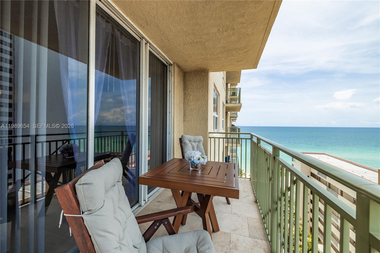 A balcony with a wooden table and chairs overlooks the ocean — 2080 S Ocean Dr, Hallandale Beach FL 33009, HALLANDALE BEACH, FL