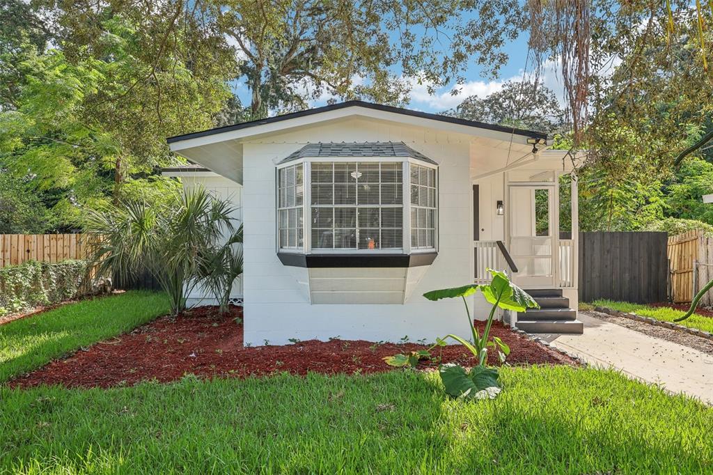 A white single-story house with a bay window, a small front porch, and red mulch landscaping — 1815 LARKIN AVENUE, ORLANDO, FL
