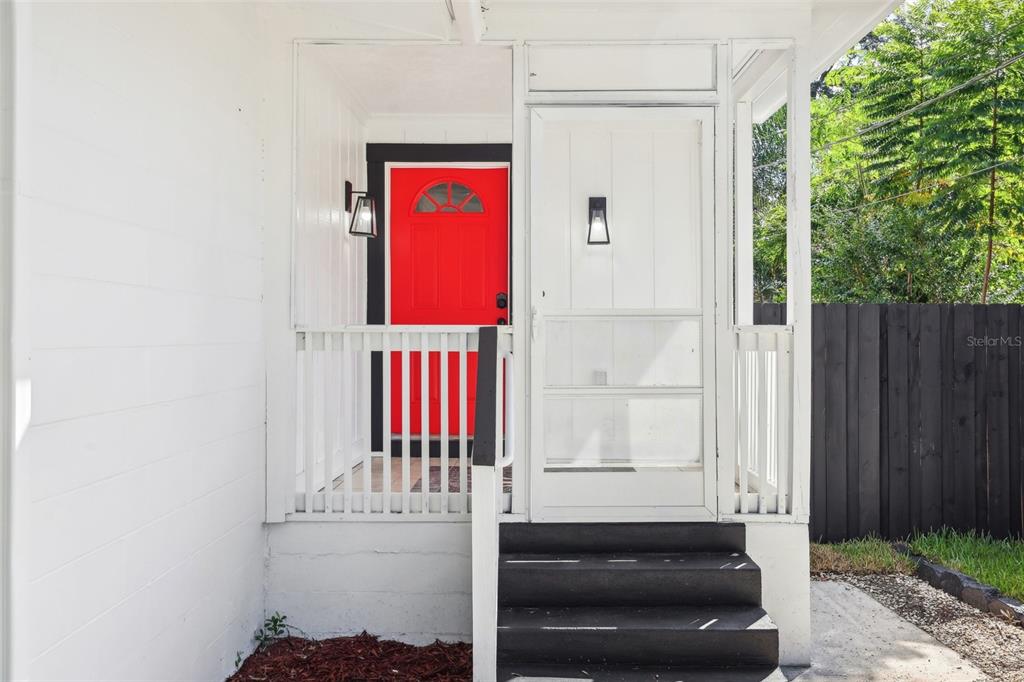 A red front door sits behind a white screen door on a small porch — 1815 LARKIN AVENUE, ORLANDO, FL