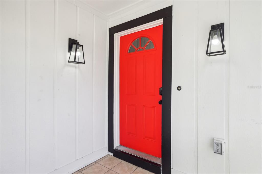 A bright red front door with a black frame is set against white vertical siding — 1815 LARKIN AVENUE, ORLANDO, FL