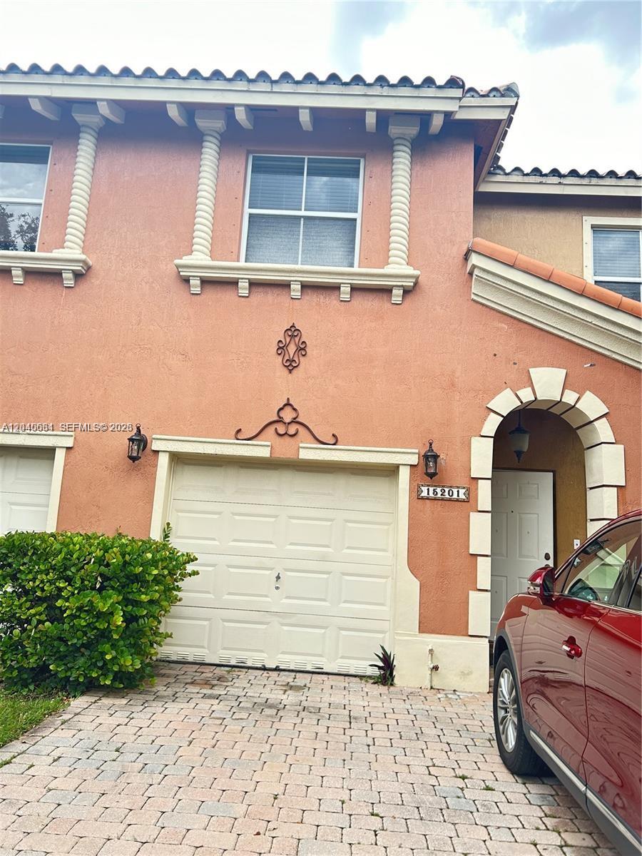The exterior of a two-story peach-colored townhouse features a garage and a front entrance — 15201 SW 30th Ter, Miami FL 33185, MIAMI, FL