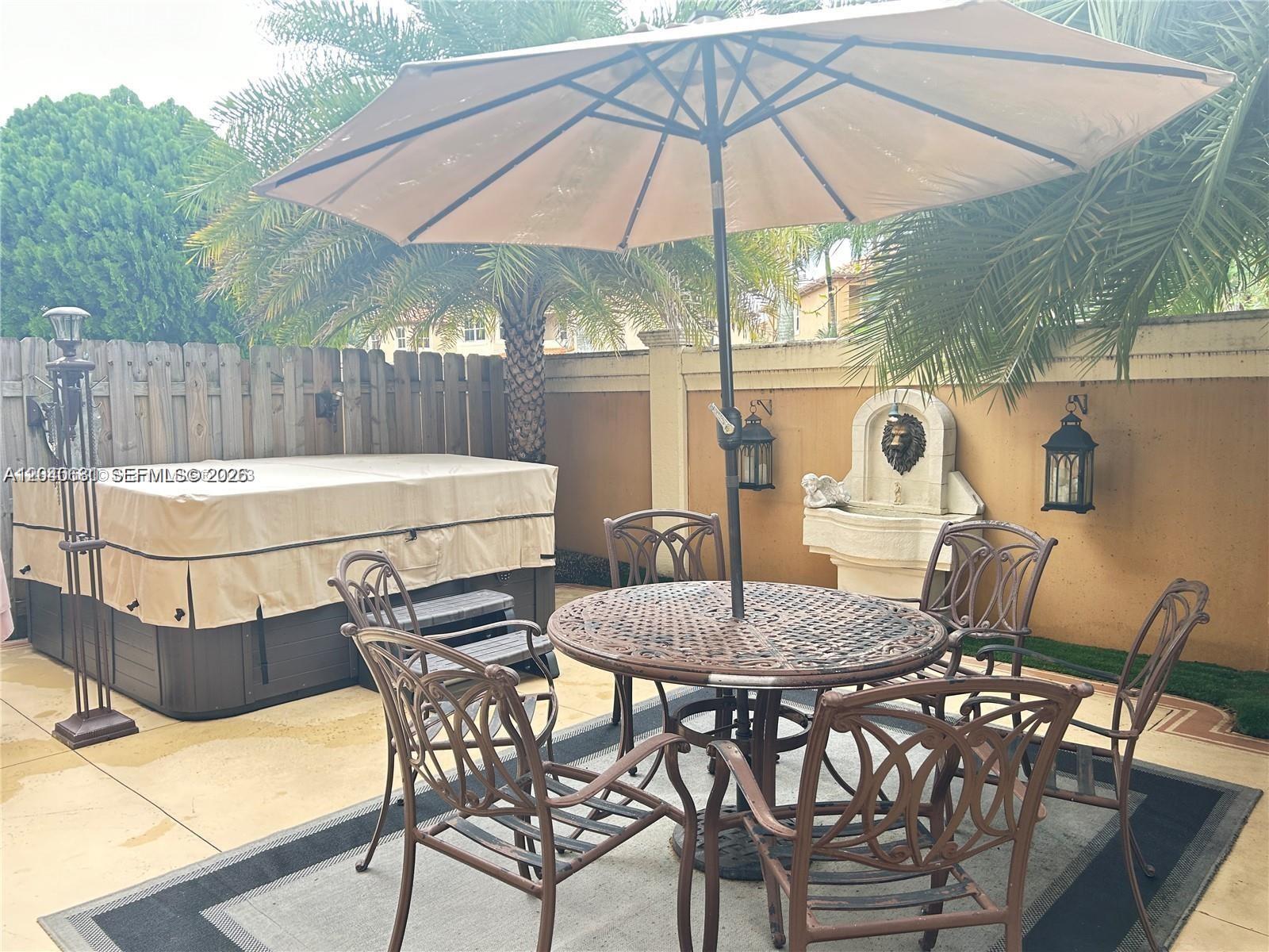 A patio area features a hot tub, a dining set with an umbrella, and a fountain — 15201 SW 30th Ter, Miami FL 33185, MIAMI, FL