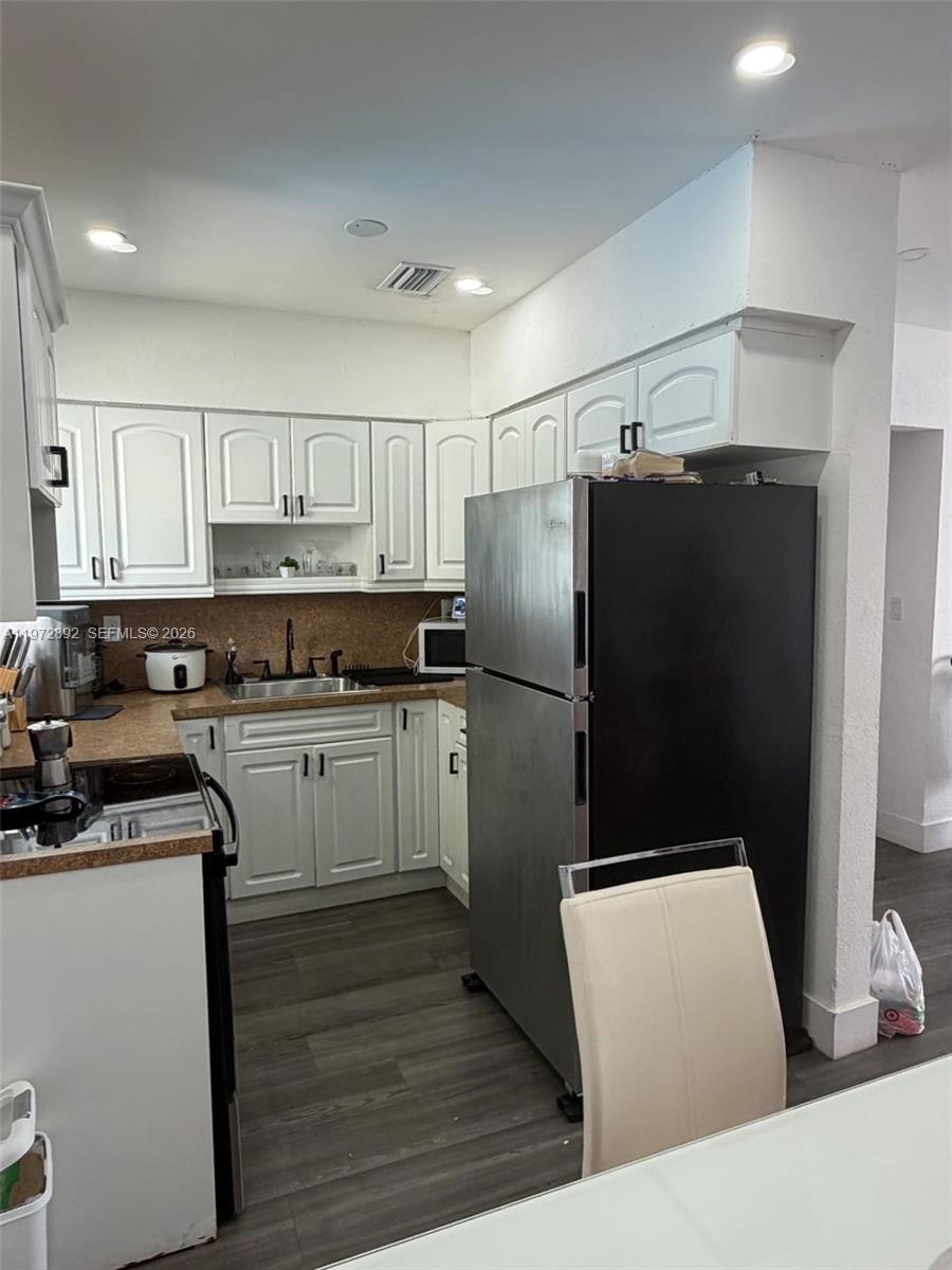 A kitchen features white cabinets, stainless steel appliances, and dark wood-look flooring — 331 NW 39th Ave # 1, Lauderhill FL 33311, LAUDERHILL, FL