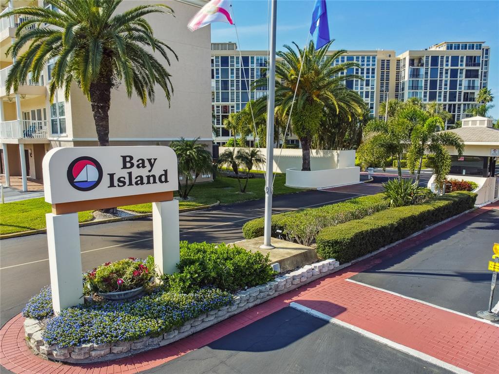 A sign for Bay Island stands in front of a multi-story apartment complex with palm trees — 7600 SUN ISLAND DRIVE S UNIT 603, SOUTH PASADENA, FL