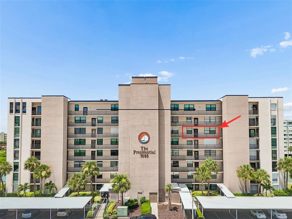 An exterior view of a multi-story apartment building with a red arrow pointing to a balcony — 7600 SUN ISLAND DRIVE S UNIT 603, SOUTH PASADENA, FL