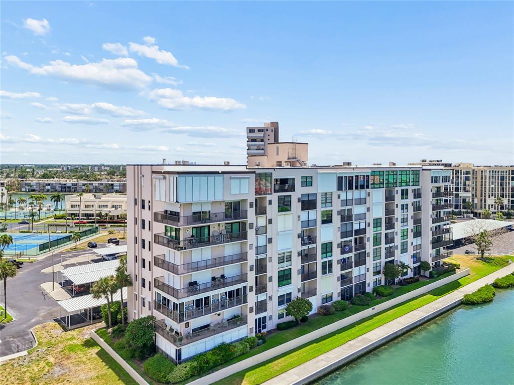 An aerial view shows a multi-story apartment building situated next to a canal and tennis courts — 7600 SUN ISLAND DRIVE S UNIT 603, SOUTH PASADENA, FL