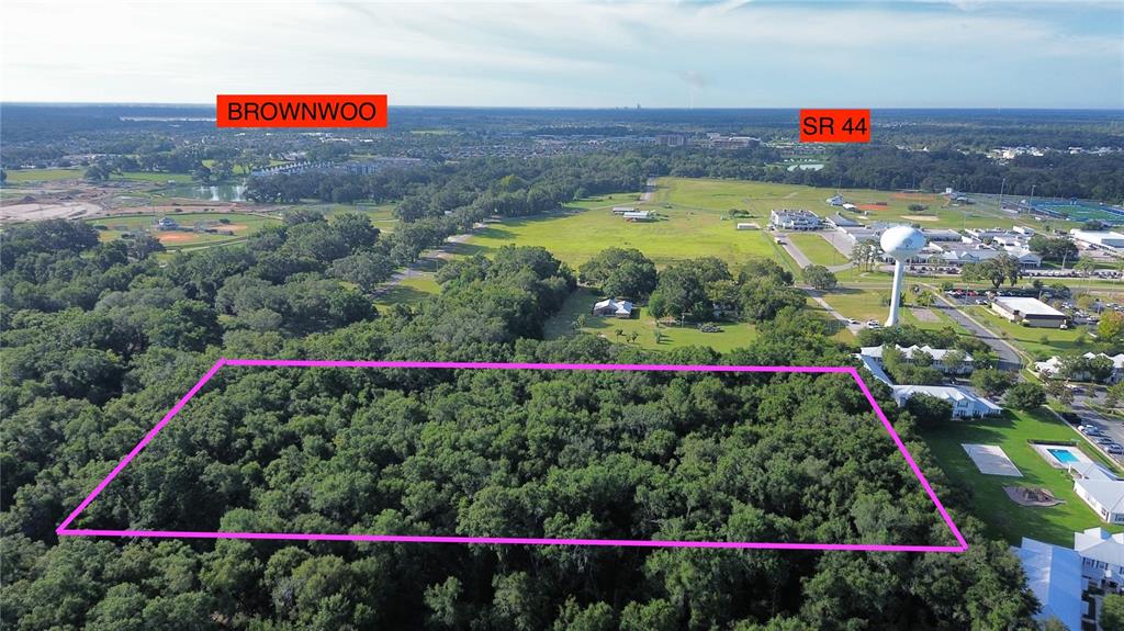 An aerial view shows a rectangular plot of wooded land outlined in pink — TBD S ST CLAIR ST, WILDWOOD, FL