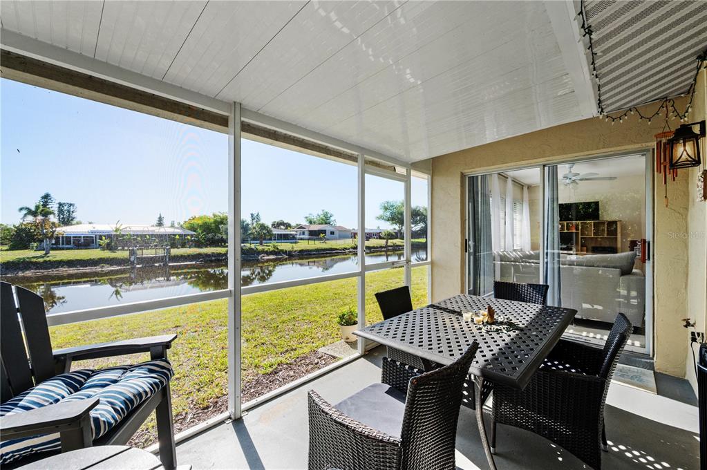 A screened-in patio features outdoor furniture overlooking a canal and residential neighborhood — 182 BOUNDARY BOULEVARD UNIT B, ROTONDA WEST, FL
