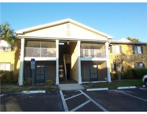 A screened-in patio with two chairs and a table overlooks a lake and grassy yard — 145 N PEARL LAKE CAUSEWAY UNIT 112, ALTAMONTE SPRINGS, FL
