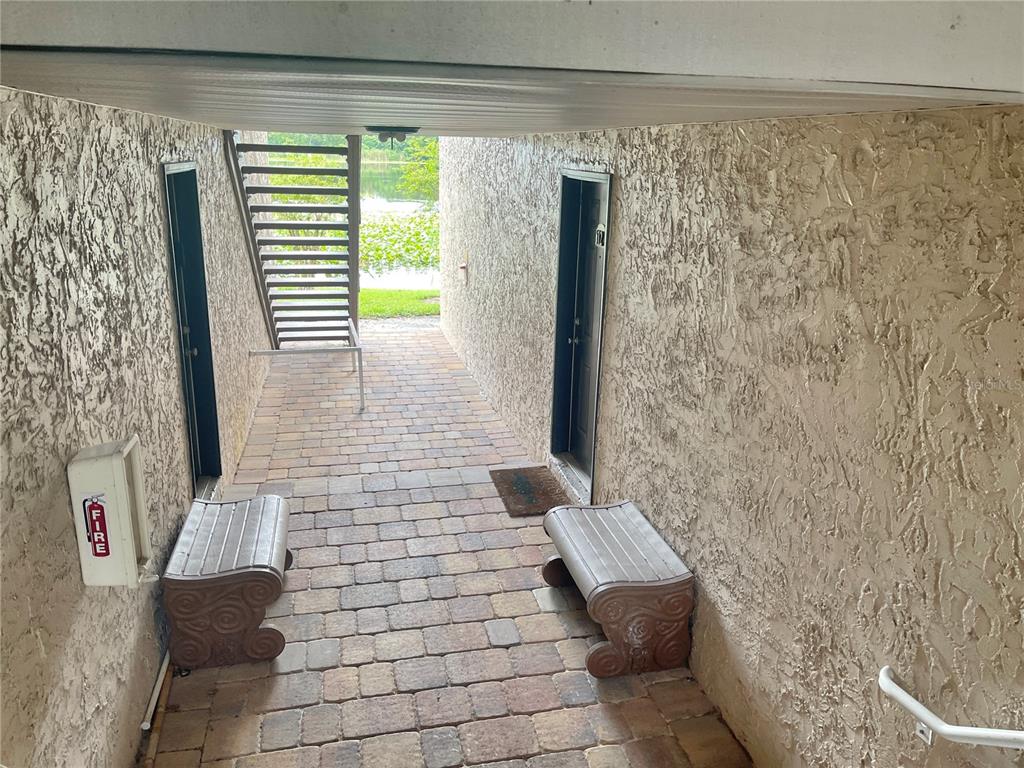 A bedroom features a bed with a gray headboard, a bench, and a corner chair — 145 N PEARL LAKE CAUSEWAY UNIT 112, ALTAMONTE SPRINGS, FL