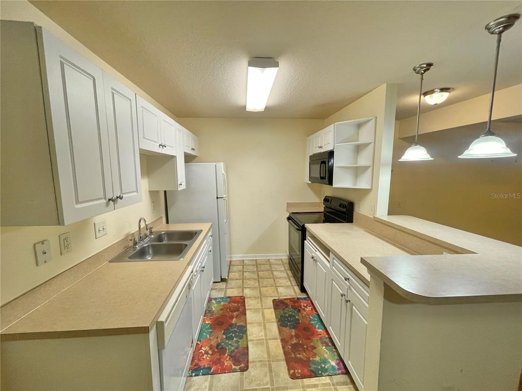 A bedroom with a bed, area rug, dresser, and chair, featuring virtual staging — 145 N PEARL LAKE CAUSEWAY UNIT 112, ALTAMONTE SPRINGS, FL