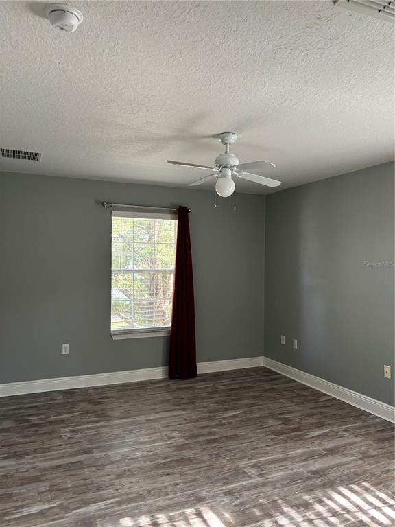 An empty room with gray walls, wood-look flooring, a ceiling fan, and a single window — 1321 EASTERN PECAN PLACE UNIT 201, WINTER GARDEN, FL