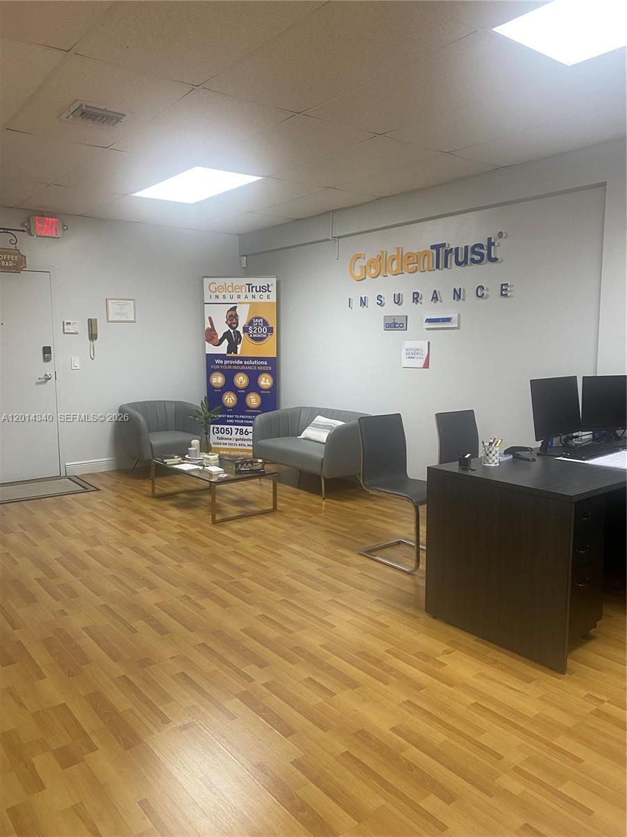 An office reception area features wood-look flooring, a seating area, and a desk with computers — 12350 SW 132nd Ct, Miami FL 33186, MIAMI, FL