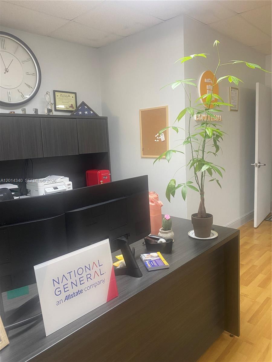 An office desk with a computer monitor, a potted plant, and a National General sign — 12350 SW 132nd Ct, Miami FL 33186, MIAMI, FL