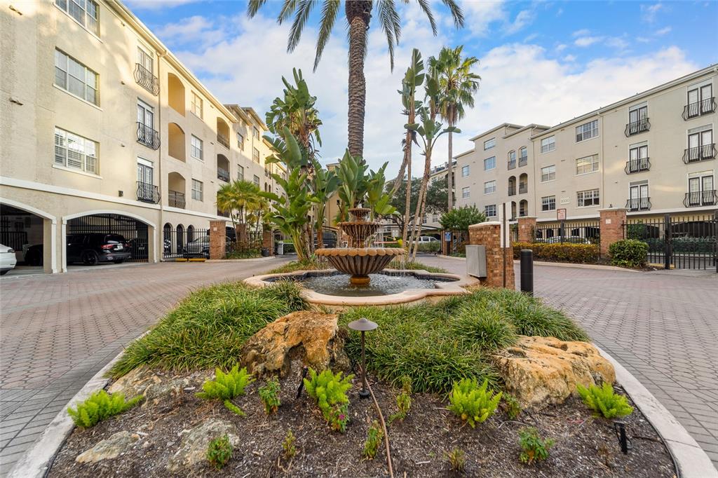 A tiered stone fountain sits in a landscaped courtyard between two multi-story apartment buildings — 501 KNIGHTS RUN AVENUE UNIT 5102, TAMPA, FL