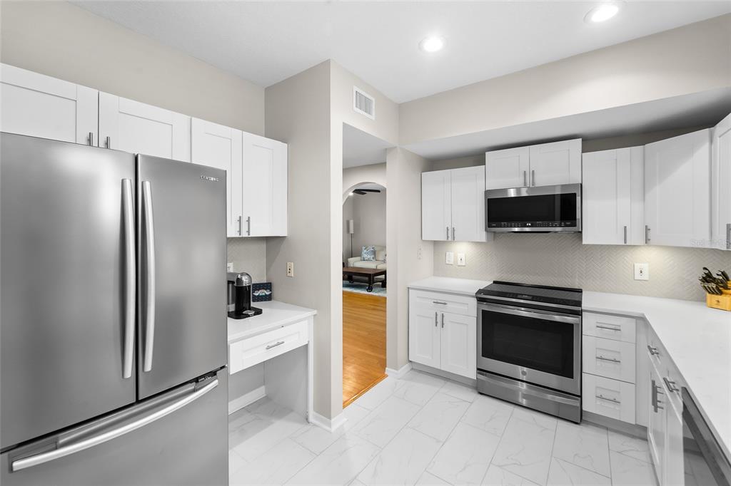 A modern kitchen features white cabinets, stainless steel appliances, and light-colored tile flooring — 501 KNIGHTS RUN AVENUE UNIT 5102, TAMPA, FL