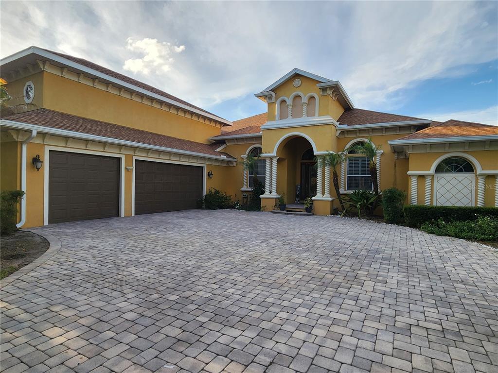 A yellow stucco house with a paved driveway and a three-car garage — 2656 WYNDSOR OAKS WAY, WINTER HAVEN, FL