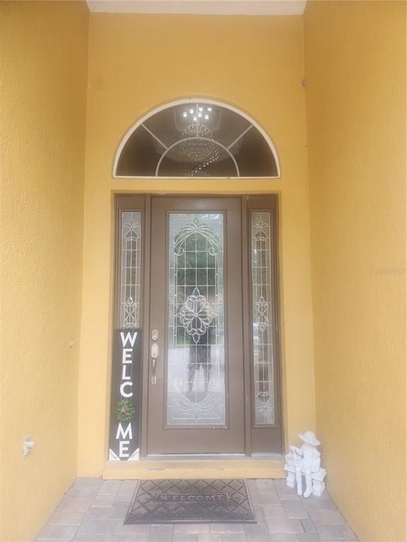 A brown front door with glass inserts and a semi-circular transom window under a porch — 2656 WYNDSOR OAKS WAY, WINTER HAVEN, FL