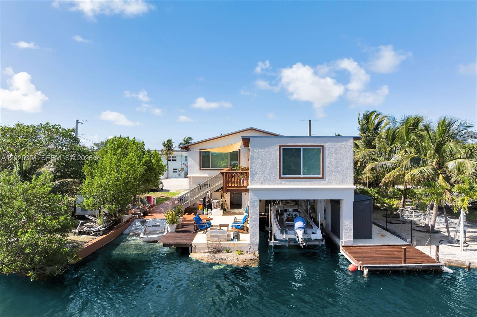 A waterfront house features a boat slip, a wooden deck, and an outdoor staircase — BIG PINE, FL