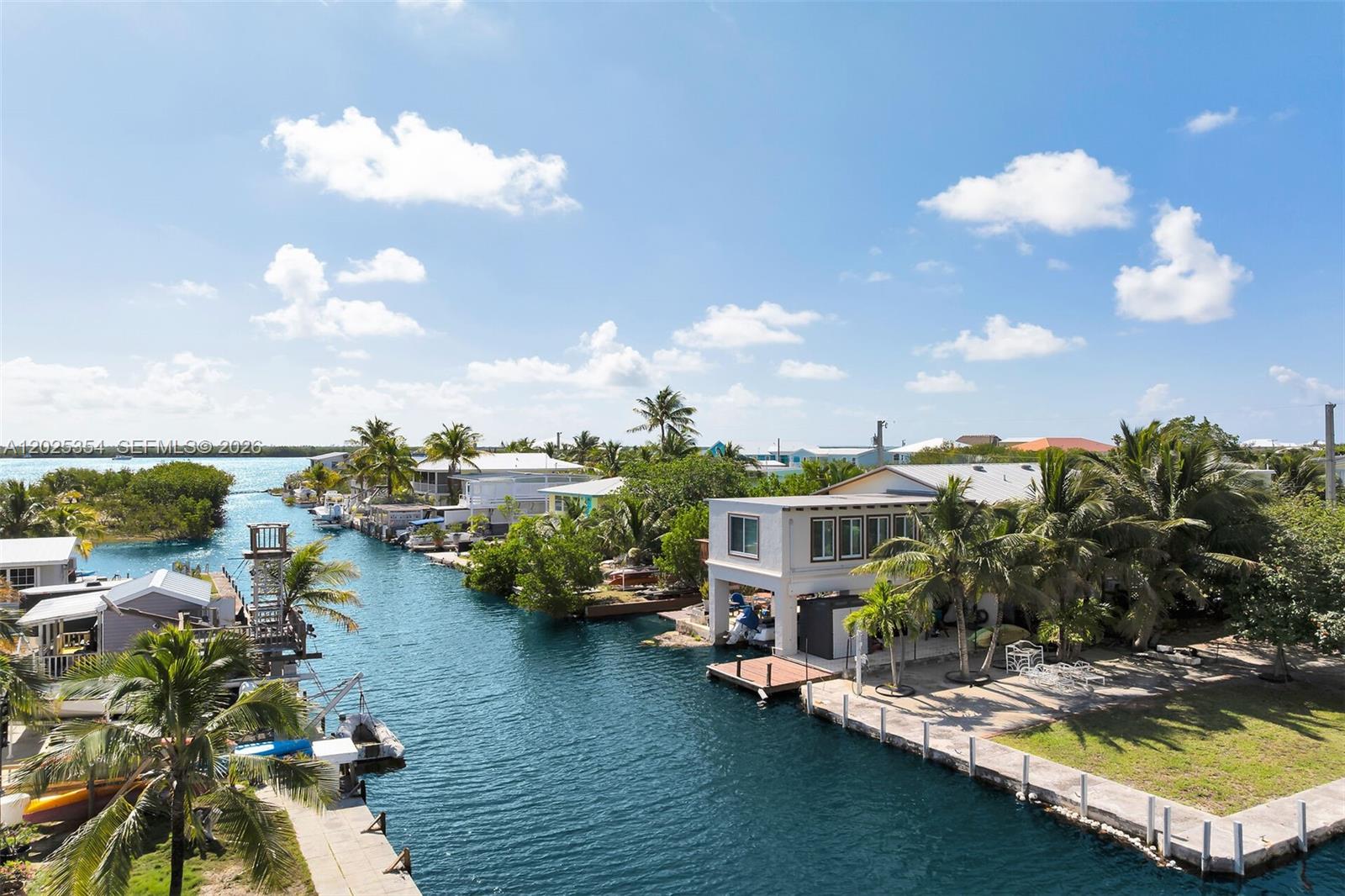 An elevated view shows a canal lined with houses, palm trees, and private boat docks — BIG PINE, FL