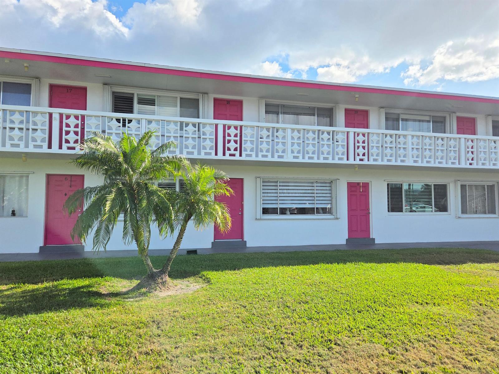 A two-story apartment building features white walls, pink doors, and a decorative balcony railing — 2180 Lake Osborne Drive # 7, FL 33461, FL