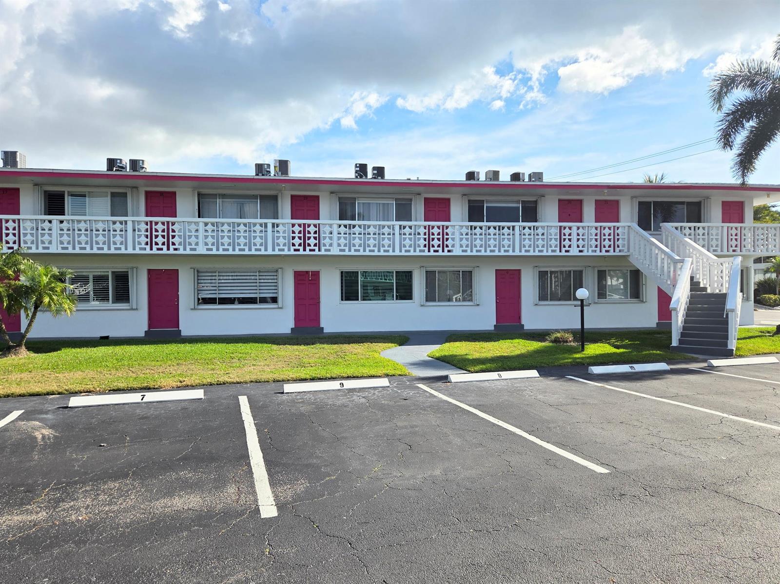 A two-story motel building features white exterior walls, pink doors, and a white balcony railing — 2180 Lake Osborne Drive # 7, FL 33461, FL