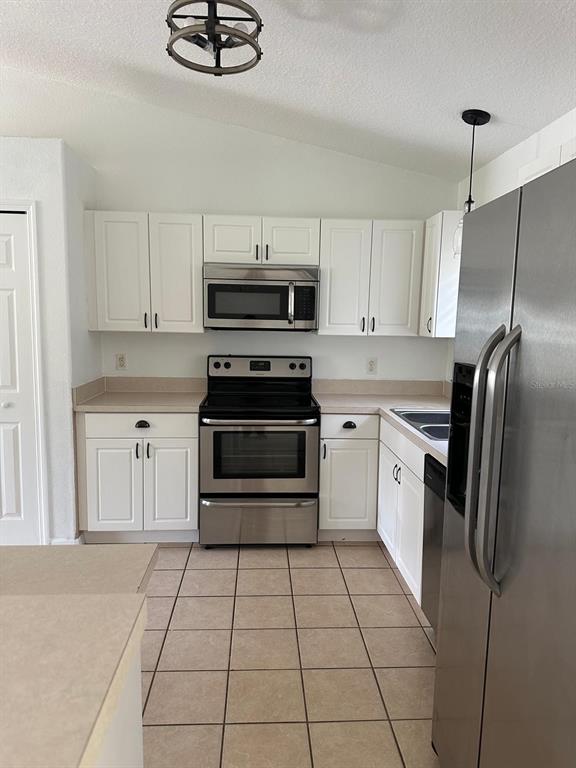 A kitchen features white cabinets, stainless steel appliances, and light-colored tile flooring — 2149 N NORMANDY BOULEVARD, DELTONA, FL