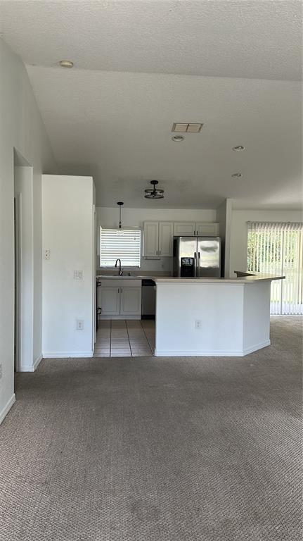A kitchen with white cabinets and a breakfast bar overlooks a carpeted living area — 2149 N NORMANDY BOULEVARD, DELTONA, FL