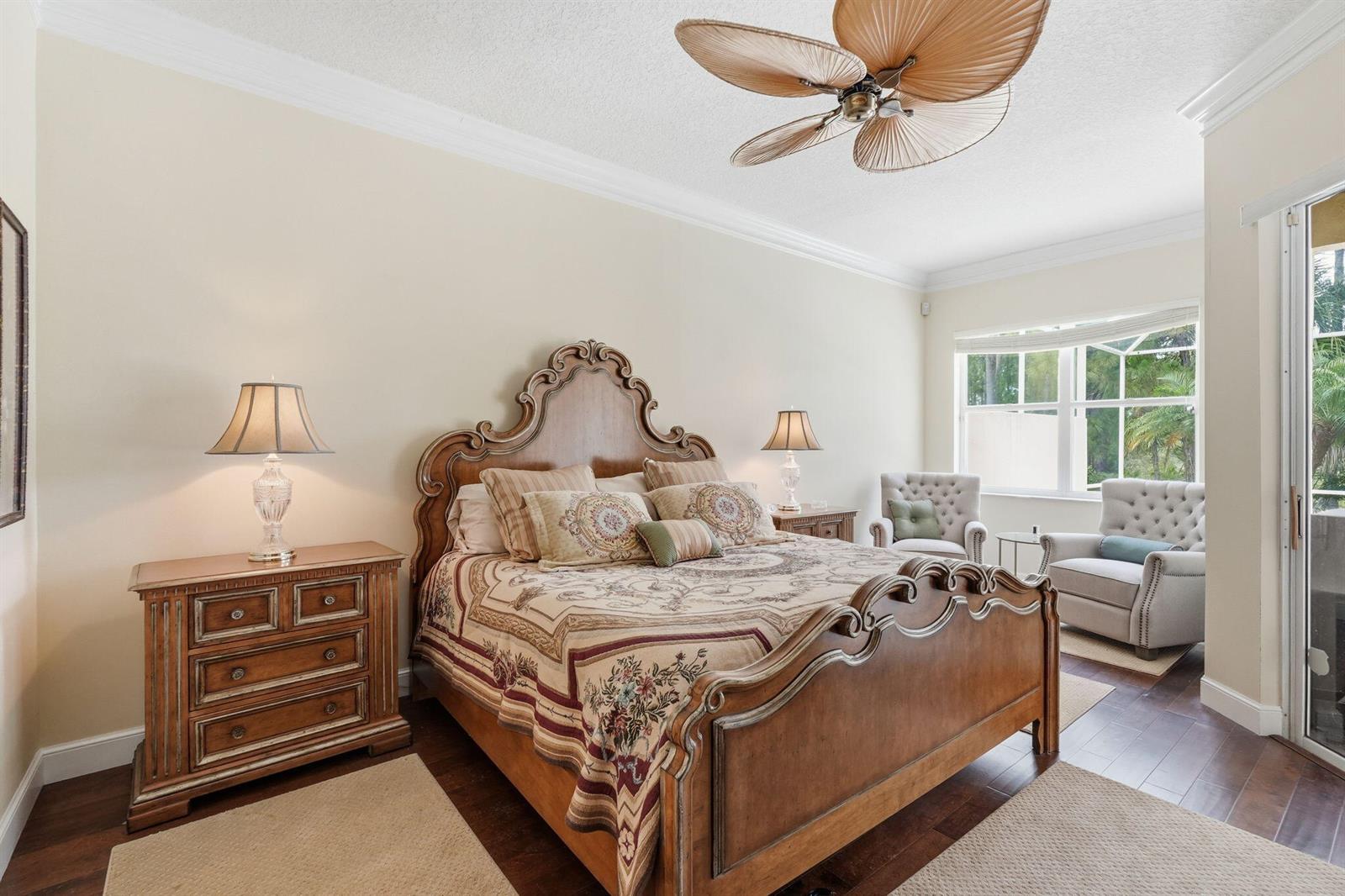 A bedroom features a wooden bed frame, two nightstands, and two armchairs near a window — 6483 SE Wild Olive Lane, Stuart FL 34997, STUART, FL