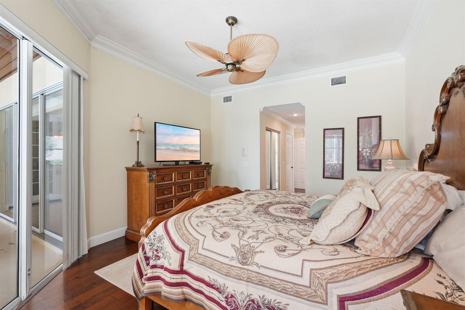 A bedroom features a wooden bed frame, a dresser with a television, and a ceiling fan — 6483 SE Wild Olive Lane, Stuart FL 34997, STUART, FL