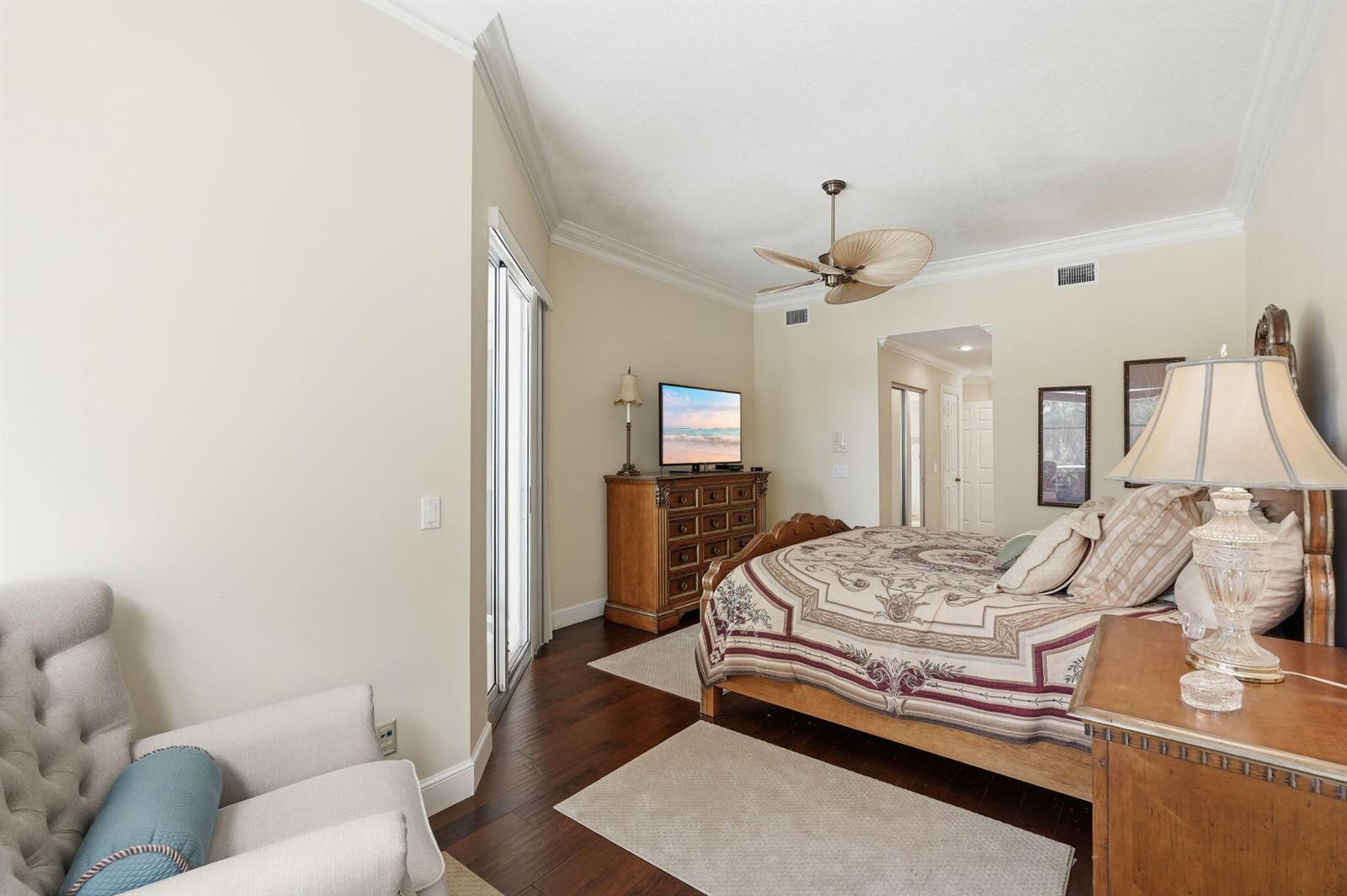 A bedroom features dark wood flooring, a ceiling fan, a bed, and a dresser — 6483 SE Wild Olive Lane, Stuart FL 34997, STUART, FL