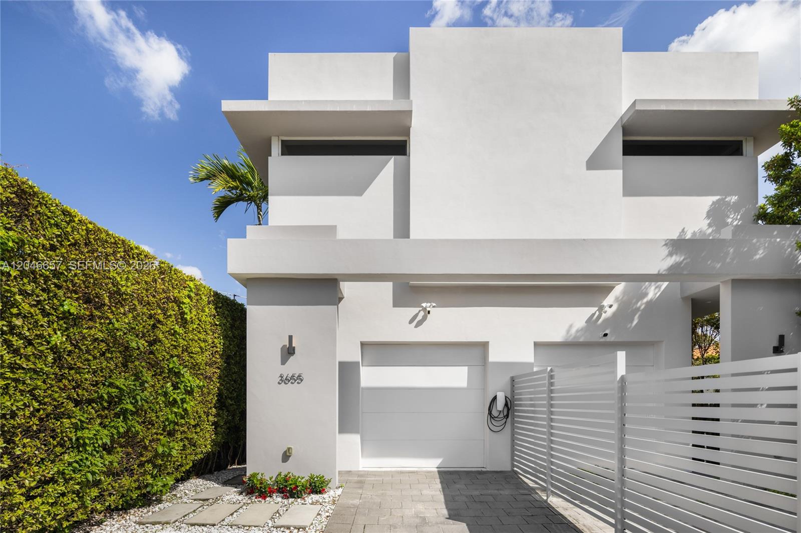 A modern two-story white house features a garage, a white fence, and a hedge — 3655 SW 25th St # 3655, Miami FL 33133, MIAMI, FL