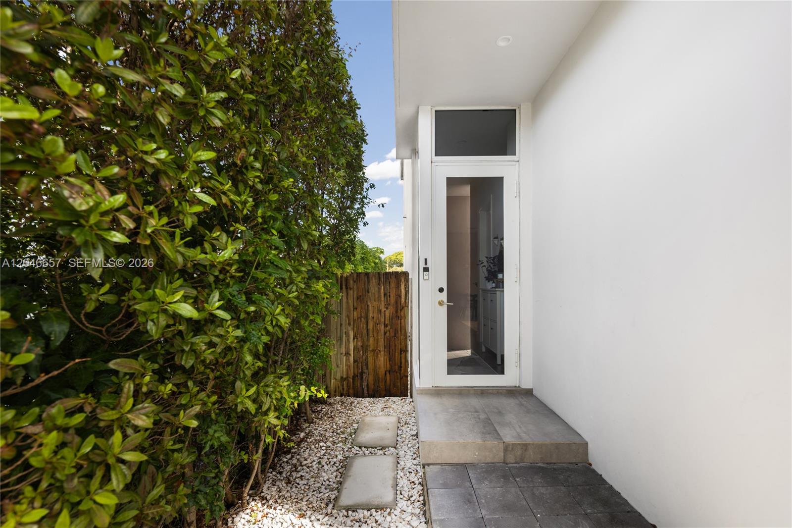 A white door with a glass panel leads to a tiled entryway beside a hedge — 3655 SW 25th St # 3655, Miami FL 33133, MIAMI, FL