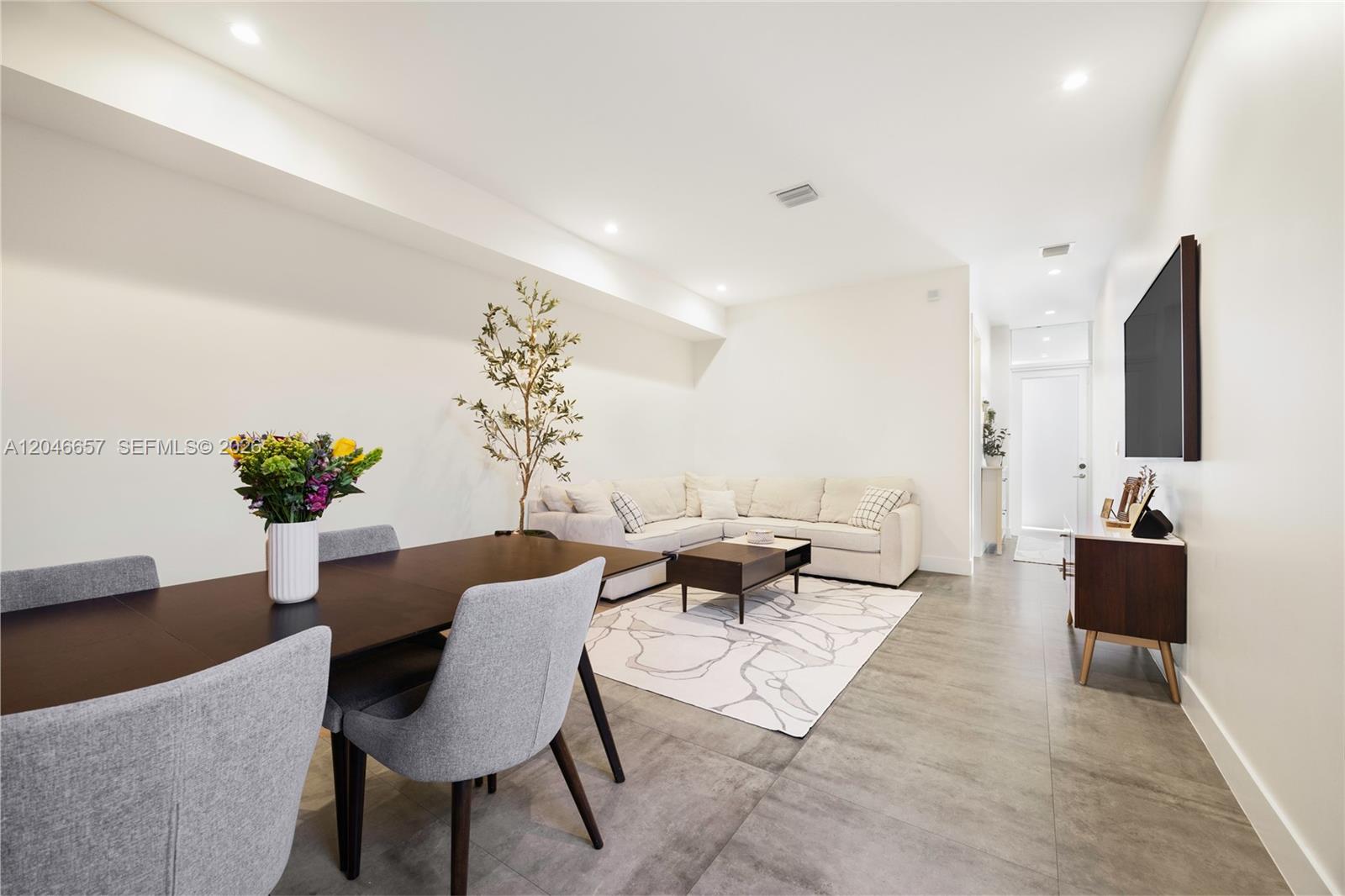 An open-concept living and dining area features tile flooring, a sectional sofa, and a table — 3655 SW 25th St # 3655, Miami FL 33133, MIAMI, FL