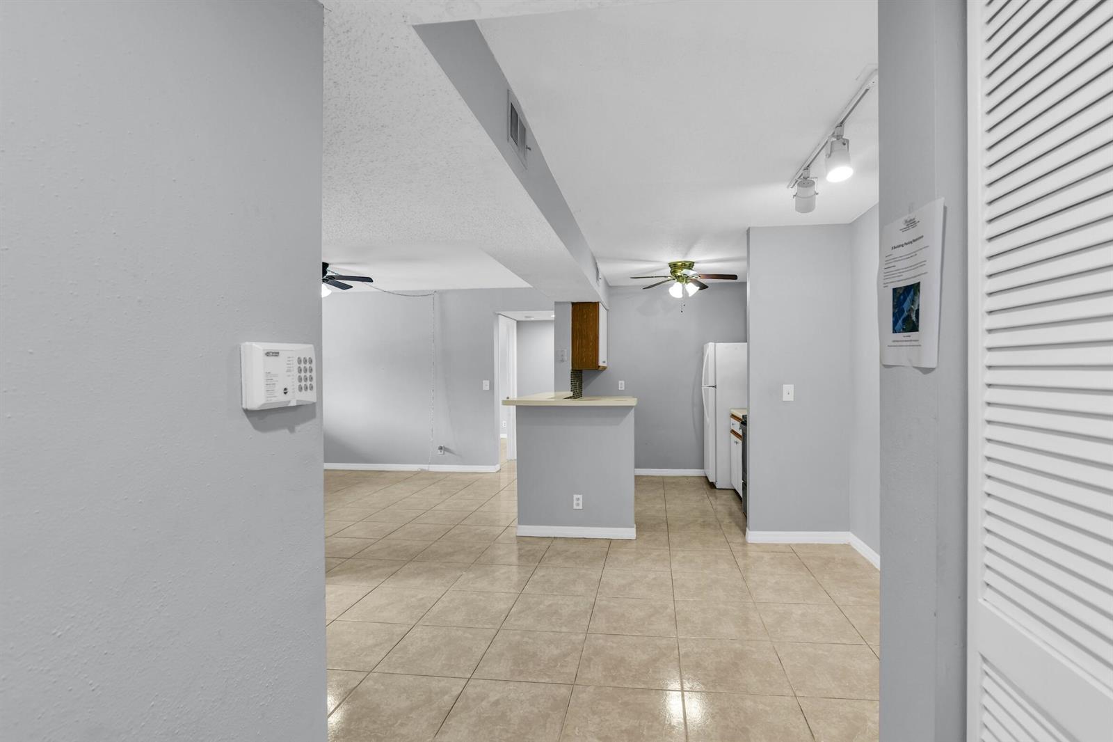 An interior view shows a tiled living area and kitchen with a breakfast bar — 3995 W Mcnab Road # B205, Pompano Beach FL 33069, POMPANO BEACH, FL