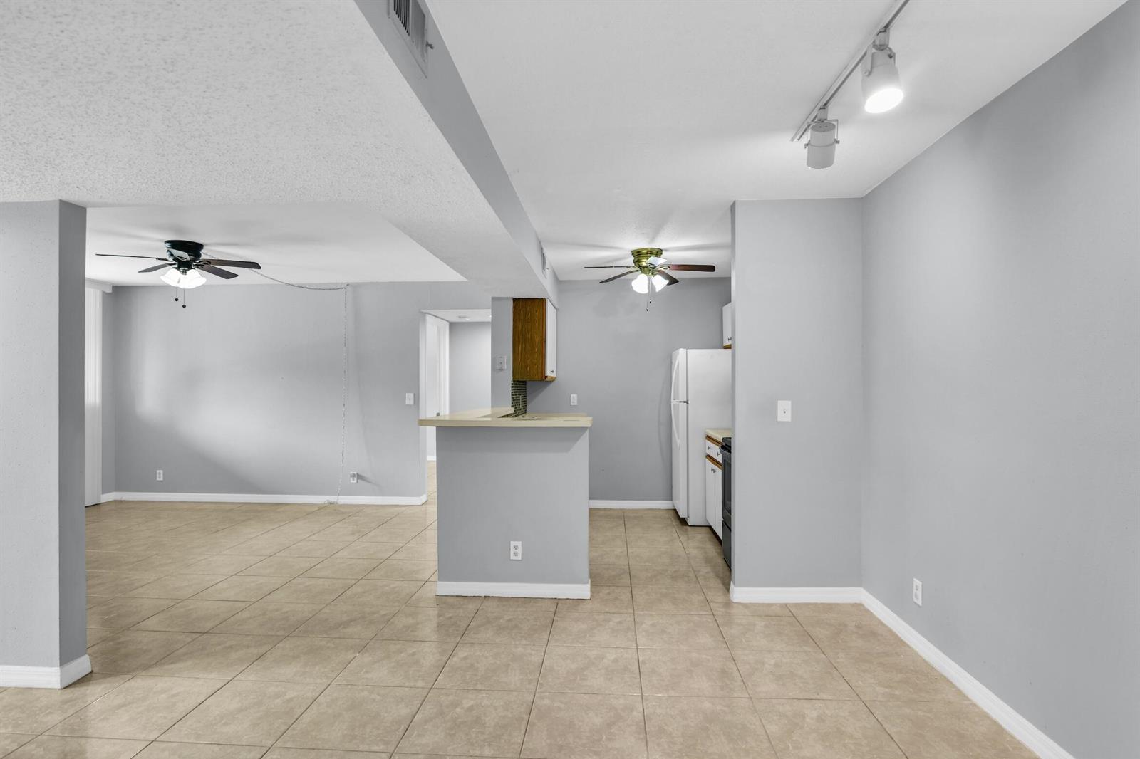 An open-concept living and kitchen area with light gray walls and beige tile flooring — 3995 W Mcnab Road # B205, Pompano Beach FL 33069, POMPANO BEACH, FL