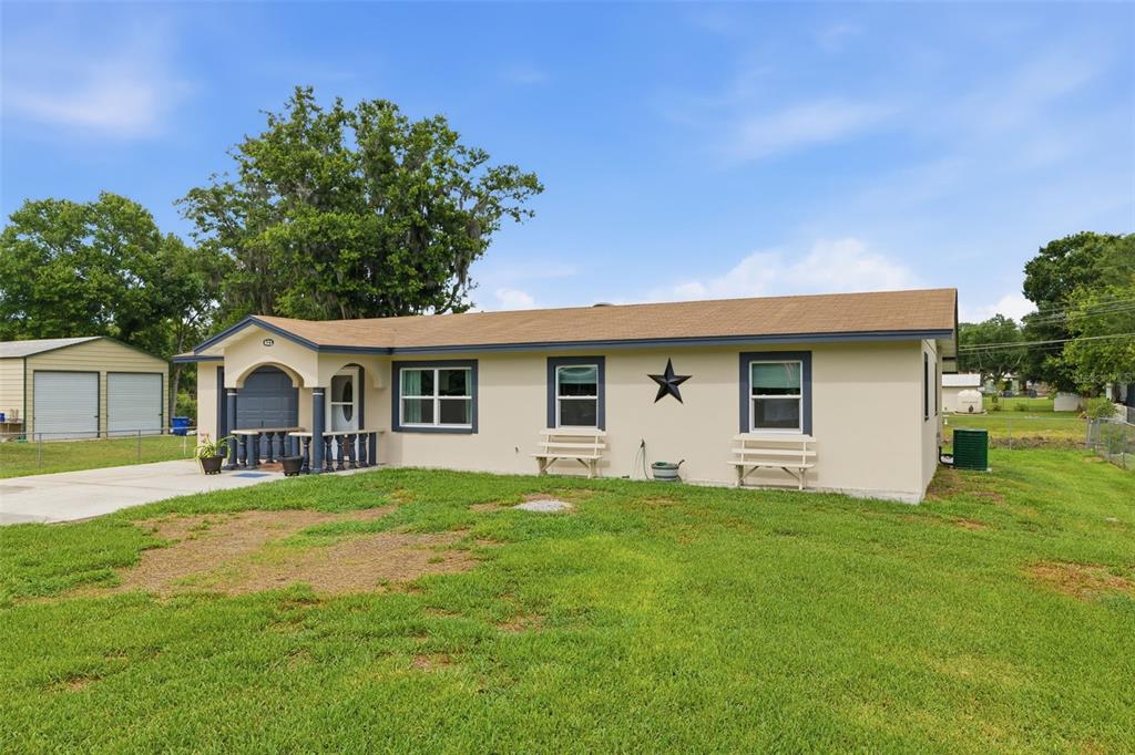 A single-story house with a tan exterior, blue trim, a covered porch, and a star decoration — 421 WATERVIEW DRIVE, POLK CITY, FL