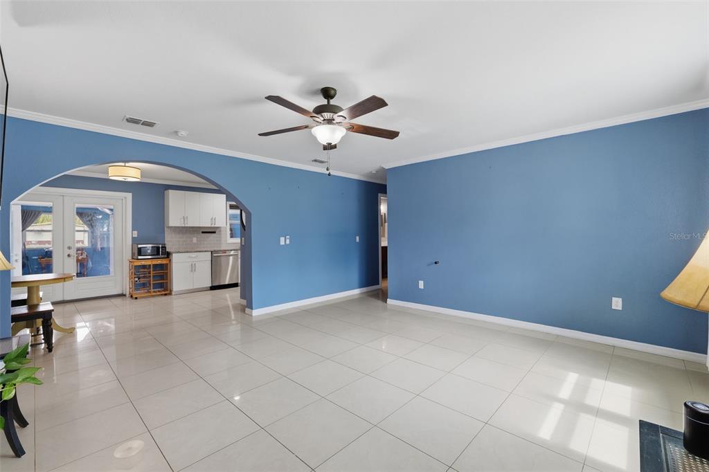 A spacious living room with blue walls and white tile floors opens into a kitchen — 421 WATERVIEW DRIVE, POLK CITY, FL