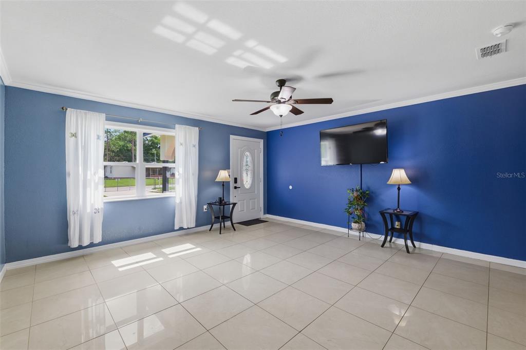 A living room with blue walls, tile flooring, a ceiling fan, and a mounted television — 421 WATERVIEW DRIVE, POLK CITY, FL