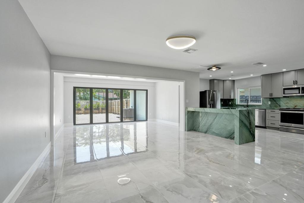 A modern open-concept living area features a green marble kitchen island and glossy tile floors — 1424 Adams Street, Hollywood FL 33020, HOLLYWOOD, FL