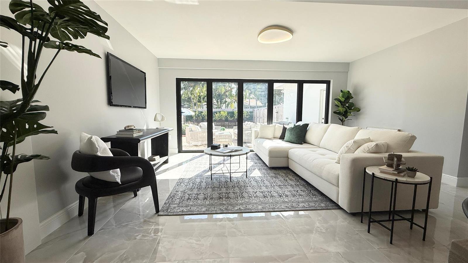 A living room features a white sectional sofa, a dark accent chair, and glass patio doors — 1424 Adams Street, Hollywood FL 33020, HOLLYWOOD, FL