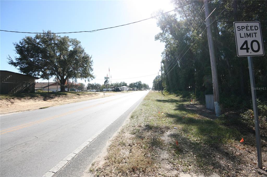 A paved road stretches into the distance past a speed limit sign and large trees — NE 36 AVE TBD, OCALA, FL