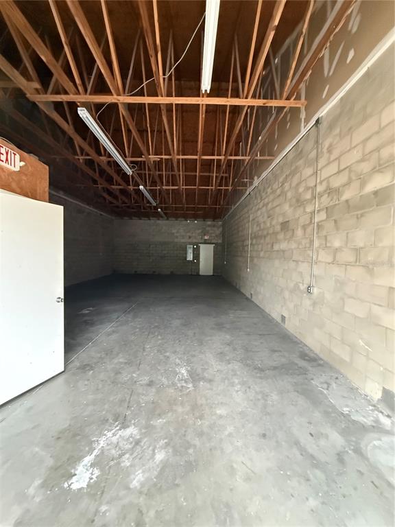 An empty industrial warehouse space features exposed wooden roof trusses and concrete block walls — 4534 NE 35TH STREET UNIT 5, OCALA, FL