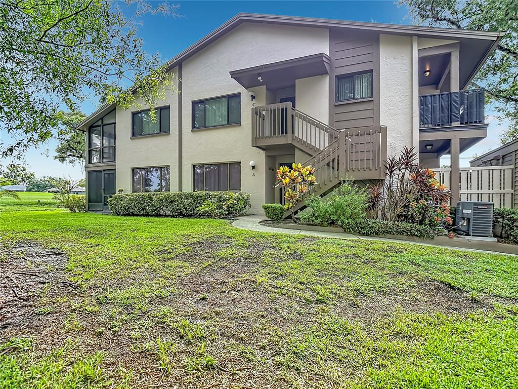 A two-story apartment building exterior features a wooden staircase leading to an upper-level unit — 13010 WEDGEWOOD WAY UNIT C, HUDSON, FL