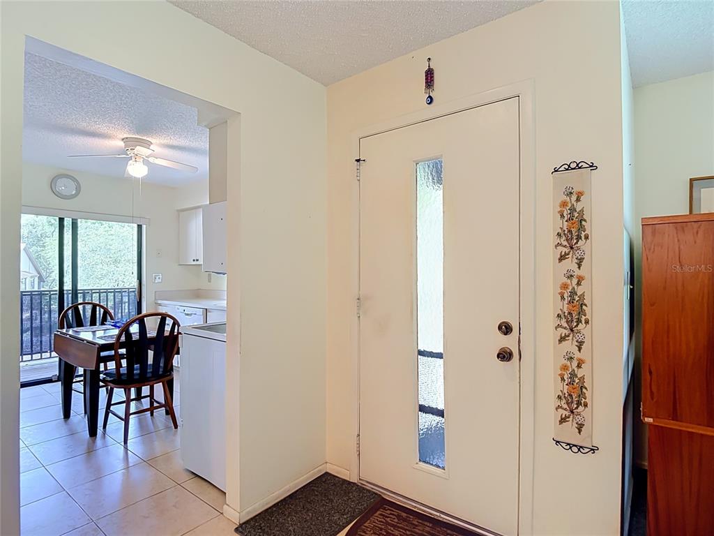 An entryway with a white front door leads into a dining area with tile flooring — 13010 WEDGEWOOD WAY UNIT C, HUDSON, FL
